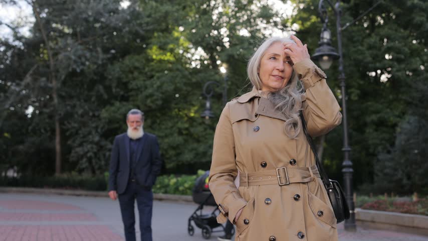 Elegant senior woman with gray hair waiting in the park