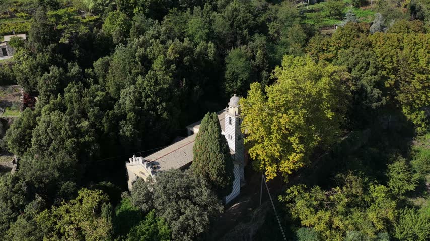 Aerial view of a historic stone church nestled within a dense forest in Vernazza, Liguria, Italy.