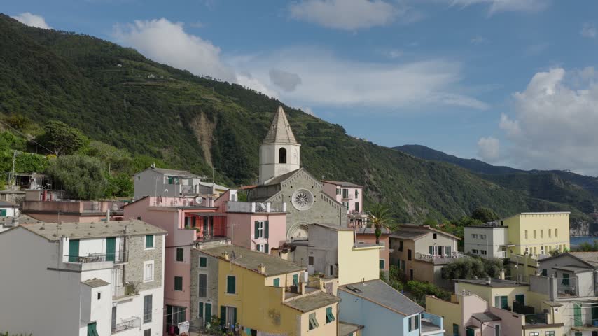Aerial view of the historic village of Corniglia with its colorful houses and the San Pietro church nestled on a hillside in Corniglia, Liguria, Italy.
