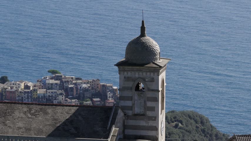 Aerial view of the historic bell tower of San Bernardino church overlooking the coastal village and the Mediterranean Sea in San Bernardino, Liguria, Italy.