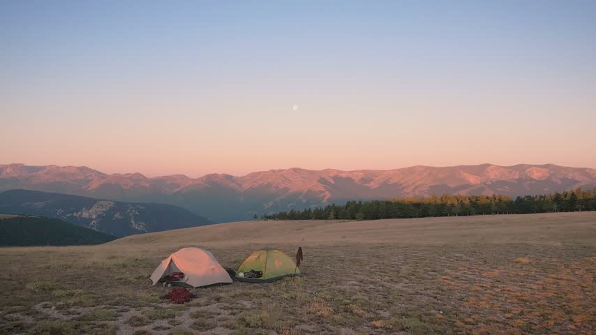 Serene mountain range sunset landscape with moonrise and rolling hills