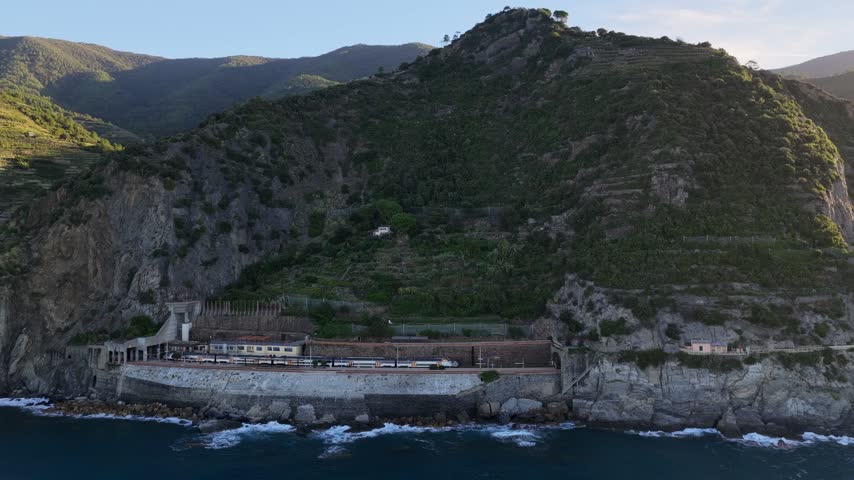 Aerial view of the train station nestled into the rocky cliffs of the coastline in Manarola, Liguria, Italy.