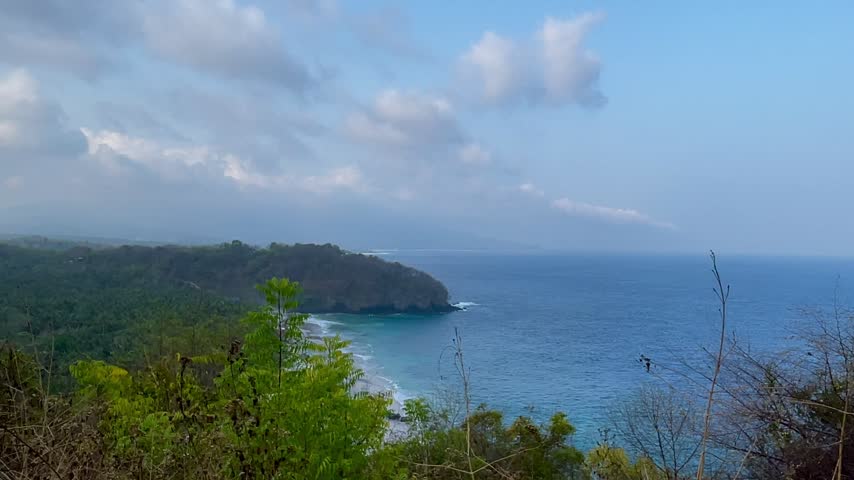 Ocean waves crashing against volcanic coastal cliff in Bali

