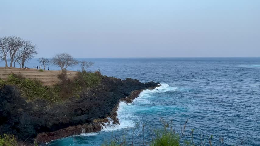 Ocean waves crashing against volcanic coastal cliff in Bali
