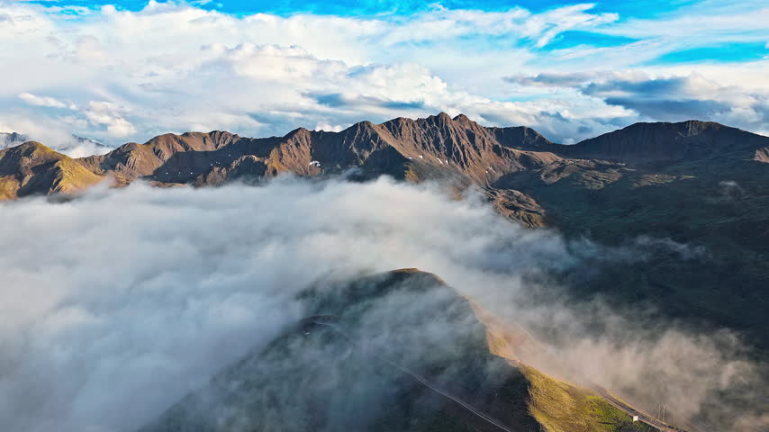 Aerial view of mountain peaks surrounded by a sea of clouds and an alpine landscape near Mount Gongga, Sichuan, China