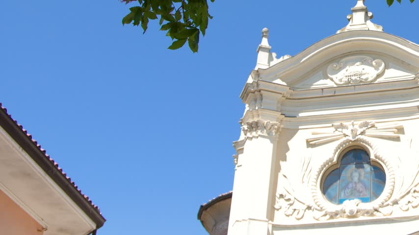 Low-angle view of an ornate Baroque church facade beneath clear blue skies in Piedmont, Italy.