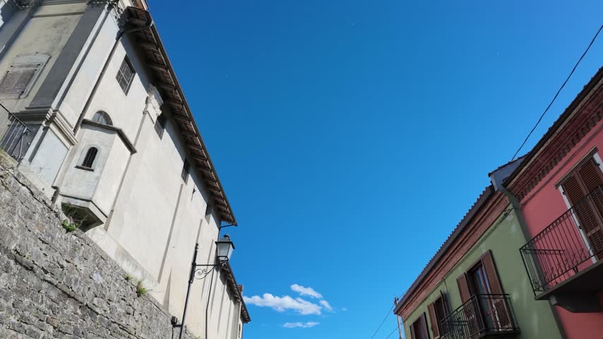 Low angle view of historic stone buildings under a clear blue sky in Piedmont, Italy.