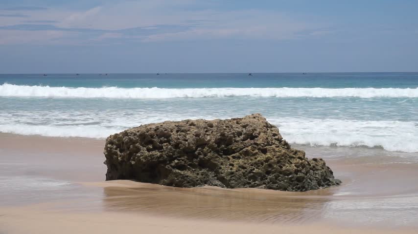 A rocky outcrop on the shore being battered by waves.