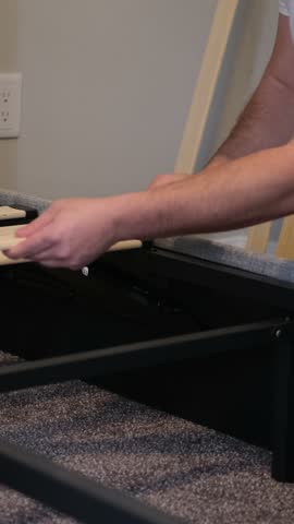 Person assembling wooden slats on a bed frame