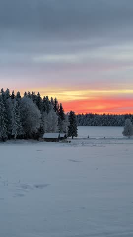 Panoramic winter landscape with snow-covered hay bales and farmhouses at sunset in Finnish Lapland, Finland