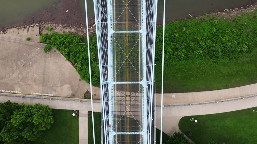 Top down aerial of the Roebling Bridge tower, roadway and American flag above the Ohio River, tracking along path
