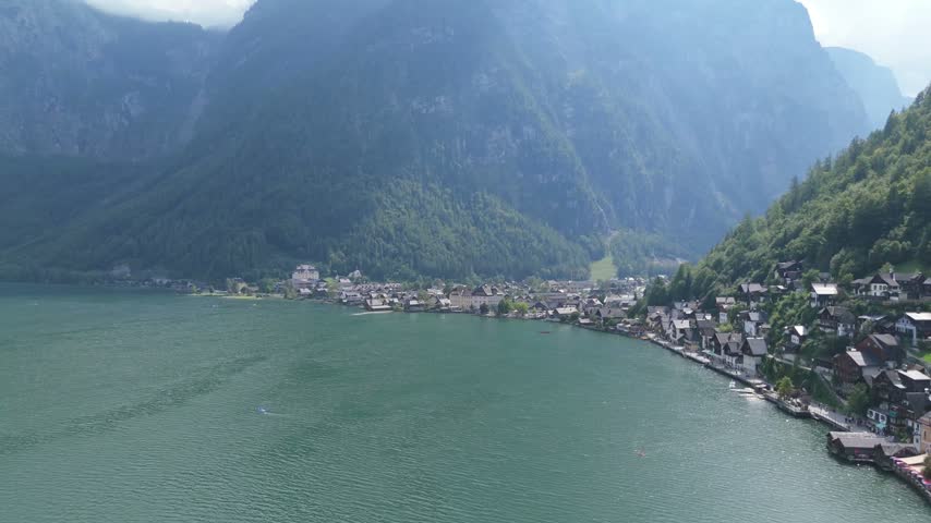 The lakeside town of Hallstatt with mountains rising behind it along the shore of the lake in Austria, aerial view