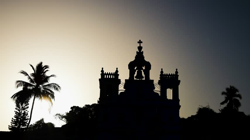 Silhouette Of A Historic Church With Cross And Bell Tower At Sunset