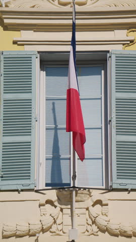 Detailed view of the Hotel de Ville, with the French flag hanging above the entrance, blue shutters, elegant stone decoration, and the "Hotel de Ville 1828" inscription, Antibes, France
