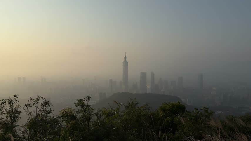 Hazy view of the Taipei skyline and Taipei 101 skyscraper at sunset from a hilltop viewpoint, Taiwan