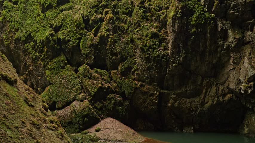 Female tourist holding a smartphone while exploring the dramatic limestone gorge and cave landscape of the Moravian Karst in the Czech Republic.