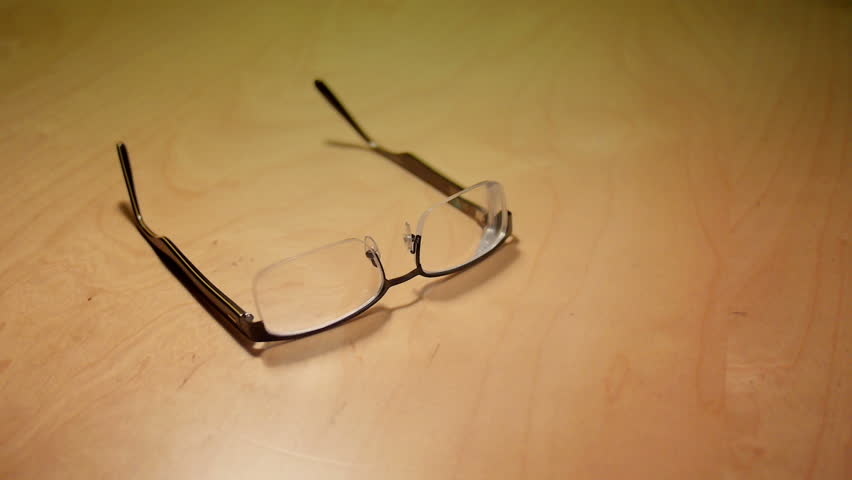 Setting down a pair of eyeglasses on a table.