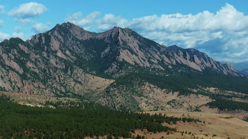 Aerial drone view South Boulder vista of the The Flatirons Colorado summer fall autumn morning sunny blue sky Front Range Rocky Mountains Foothills City of Boulder nature landscape backwards motion