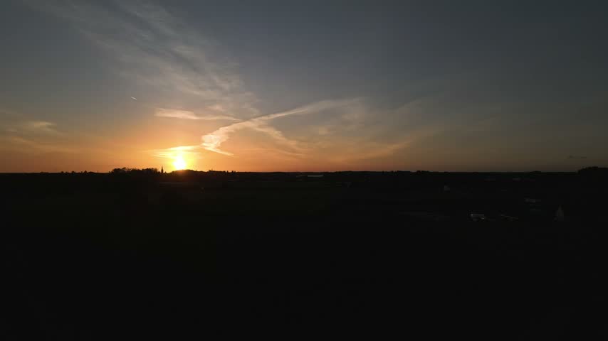 Putte township in Belgium with a dramatic silhouette against a colorful sunset sky and soft clouds.