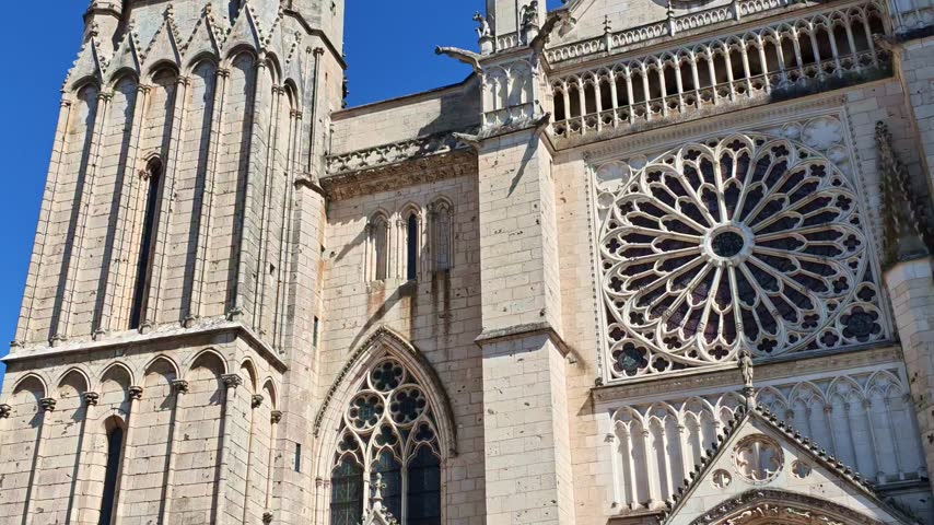 Panning exterior shot of the gothic Cathedral of St Peter or Cathedrale Saint-Pierre de Poitiers facade showing an ornate rose window, pointed arches and carved stone details, Poitiers, France