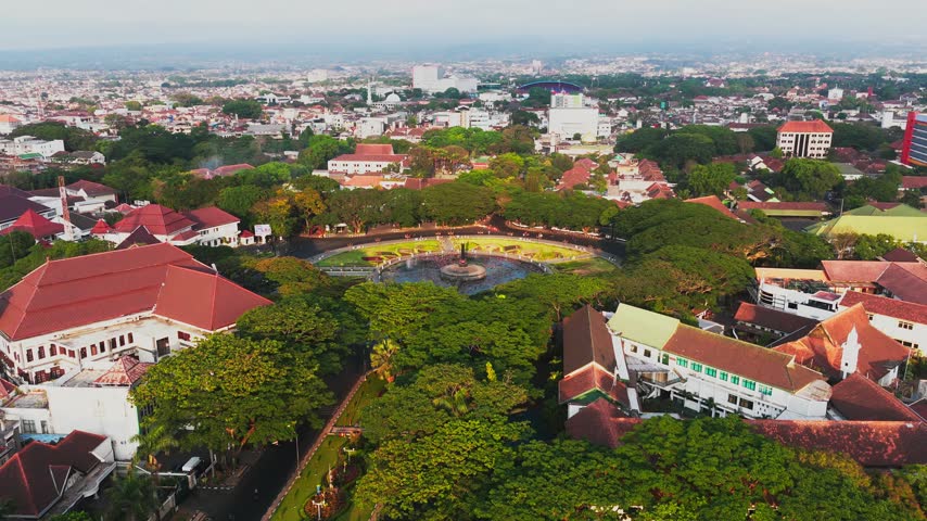 Aerial view of Malang City Hall surrounded by lush trees and historic buildings in the city center of Kecamatan Klojen, Jawa Timur, Indonesia.