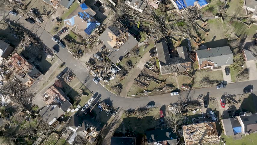 Aerial view of suburban houses destroyed by tornado storm with broken trees and debris covering streets in rural community.