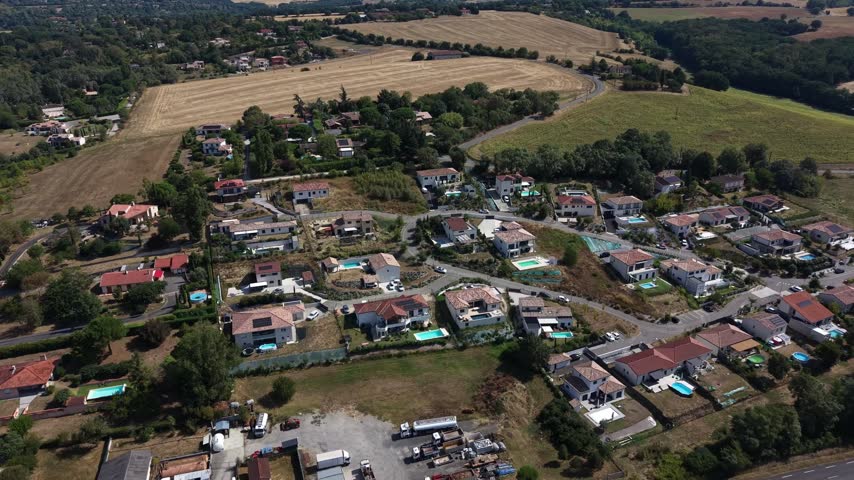 Houses with pools near Aureville as the drone pulls back to reveal the fields