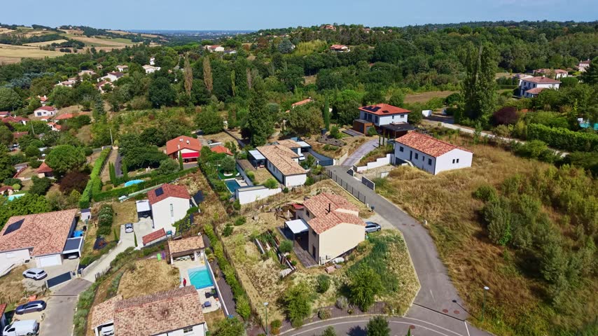Houses with pools near Aureville as the drone climbs to reveal wooded hills