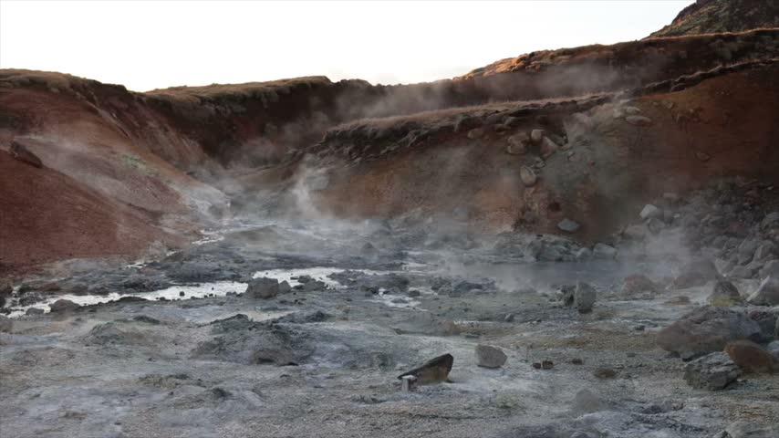 Steam rising from geothermal ground in Iceland, showing active geothermal activity in a dramatic volcanic landscape.