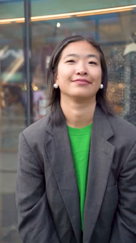 young asian smiling woman holding shopping bags in front of a shop during joyful christimas winter season