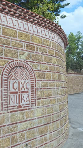 Byzantine-style cross with the inscription IC XC NIKA on a curved stone and brick wall of an Orthodox church on Aegina island, Greece. Vertical video.