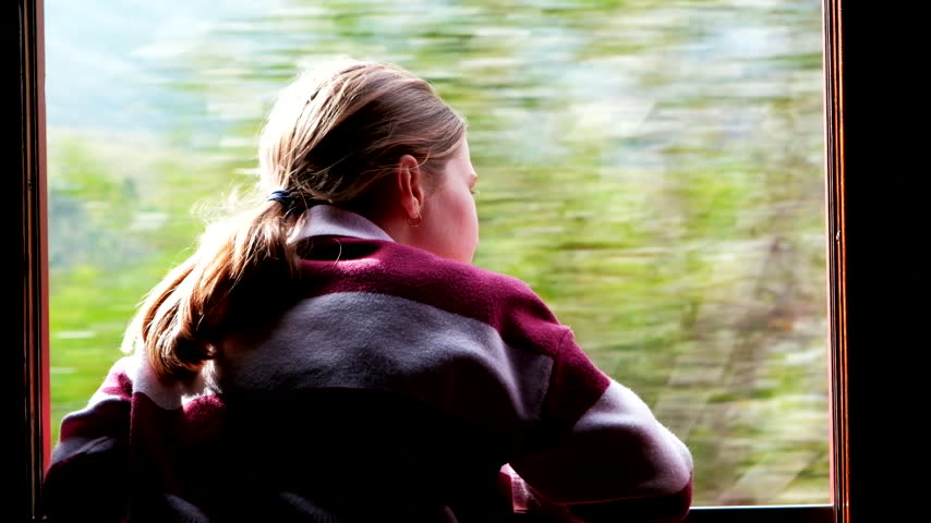 Wind through hair of pretty young girl on train ride staring out of window