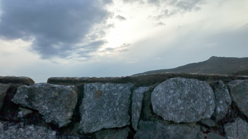 Scenic reservoir landscape with mountain slopes, forest and reflective water under a cloudy sky.