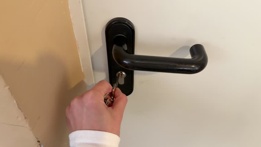 Hand unlocking door with key in keyhole close up