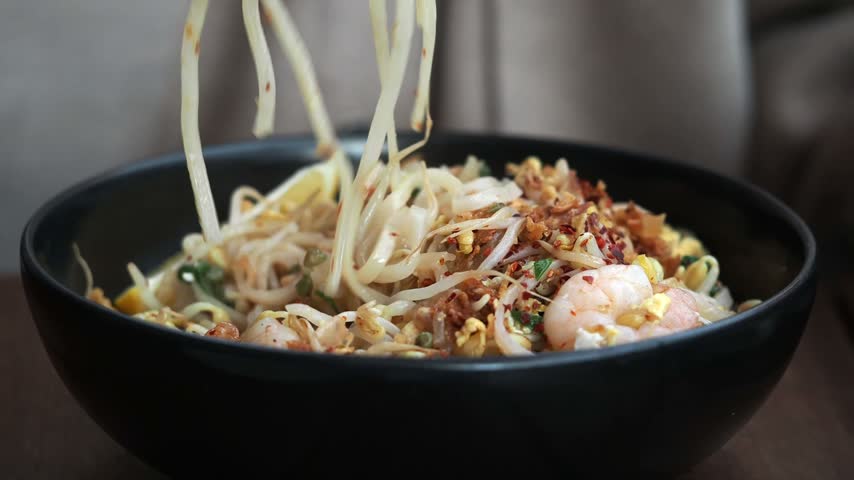 Enjoying a bowl of noodles with shrimp and vegetables