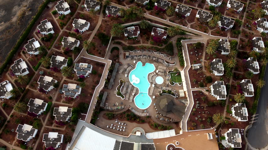 An aerial view of a resort with multiple pools buildings and landscaping