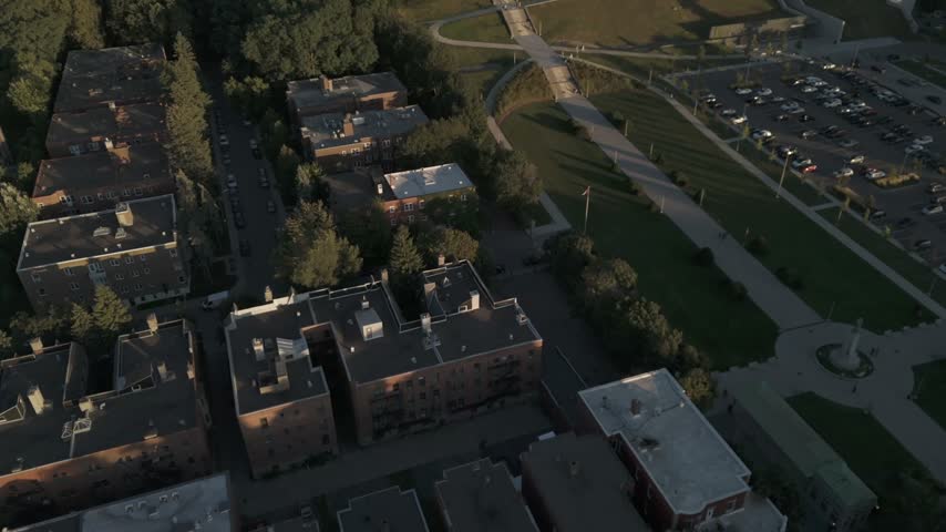 A cinematic drone shot reveals the historic Saint Josephs Oratory of Mount Royal in Montreal, surrounded by lush green trees during a warm sunset.