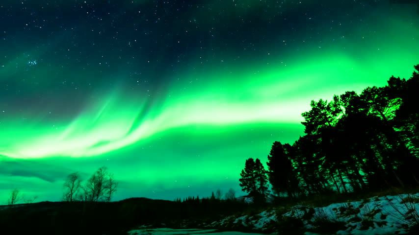 Vivid green aurora borealis over a snow-covered silhouetted landscape at Håkøybotn in Tromsø municipality, Troms, northern Norway, timelapse view