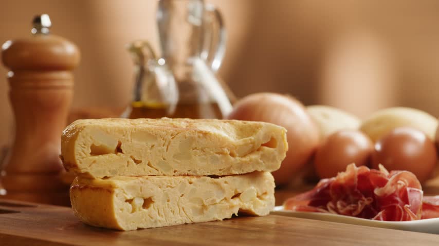 Spanish omelette with jamon serrano, tortilla and iberico cured ham appetizer on wooden table, traditional Spanish breakfast close up in cafe