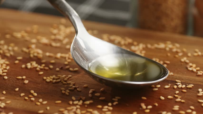 Linseed oil pouring into spoon, flaxseed oil with flax seeds on wooden table, healthy organic omega 3 superfood oil macro close up