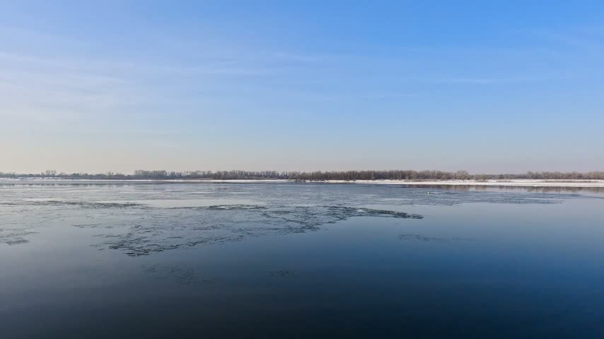 Snow river winter landscape. Frozen ice and snow by river. Spring thawed ice on water.