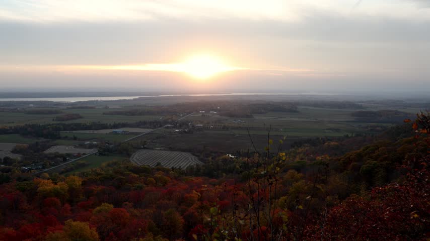 Sunset over wide autumn valley with red foliage forest. Lookout in Gatineau Park, Quebec, Canada.