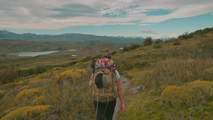 Following behind a hiker walking the iconic W Trek in Torres del Paine, surrounded by the remote wilderness, Pagatonia, Chile