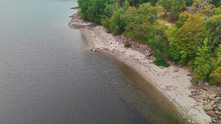 Aerial view of Harriman Reservoir with sandy beach, rocky shoreline, calm water, and dense forest, ideal for travel, outdoor recreation, summer vacations, and scenic nature landscapes.