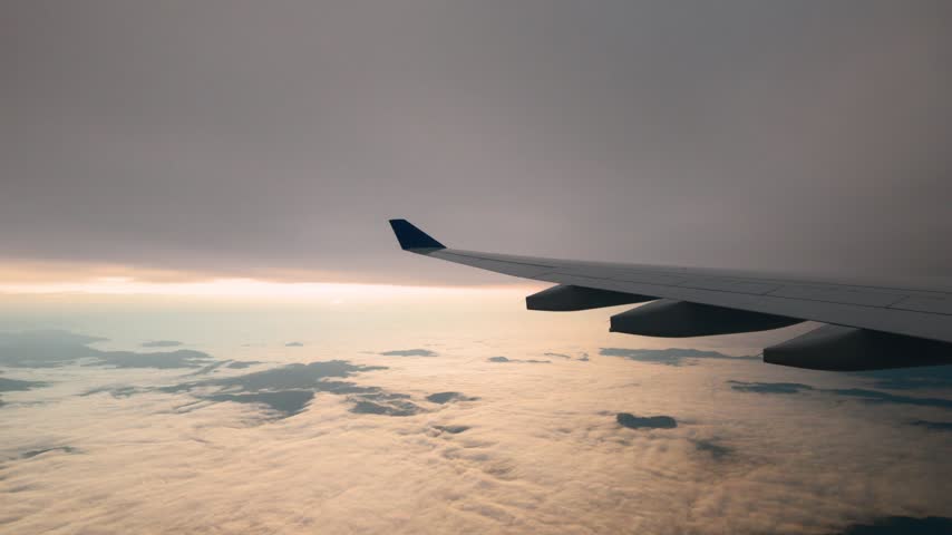 Airliner wing glides above a white layer of fog and low clouds under an overcast sky with a faint sun before landing in Sao Paulo.