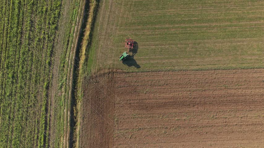 Aerial view of a tractor plowing a field in Milan, Lombardy, Italy.