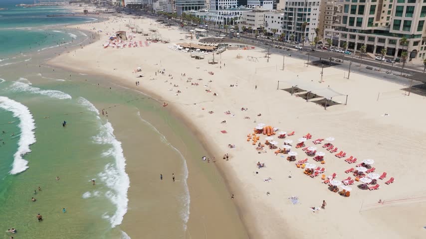 Aerial view of the sandy beach in Tel Aviv-Yafo with people relaxing on lounge chairs, umbrellas, and swimming in the Mediterranean Sea, Tel Aviv-Yafo, Tel Aviv District, Israel.