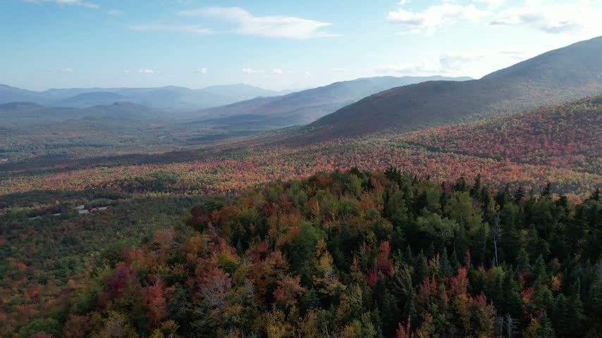 Aerial backlit crimson fall forest mountains with hazy sun flare, Adirondacks New York