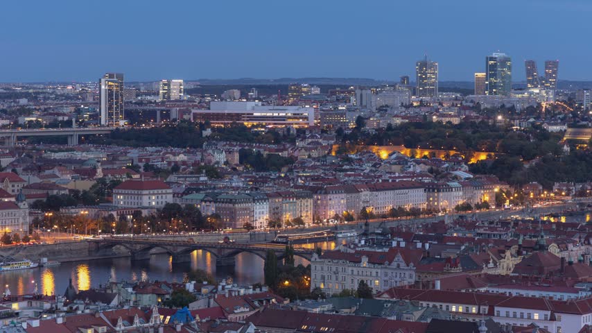 Aerial view of the historic Prague skyline at dusk with illuminated buildings, bridges over the Vltava river, and modern skyscrapers in the distance, Prague, Prague, Czechia.