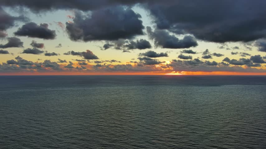 Aerial view of sunset over the Adriatic Sea with dramatic clouds over the horizon in Montenegro.